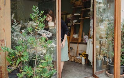 Asian florist turning a signboard on a store wall